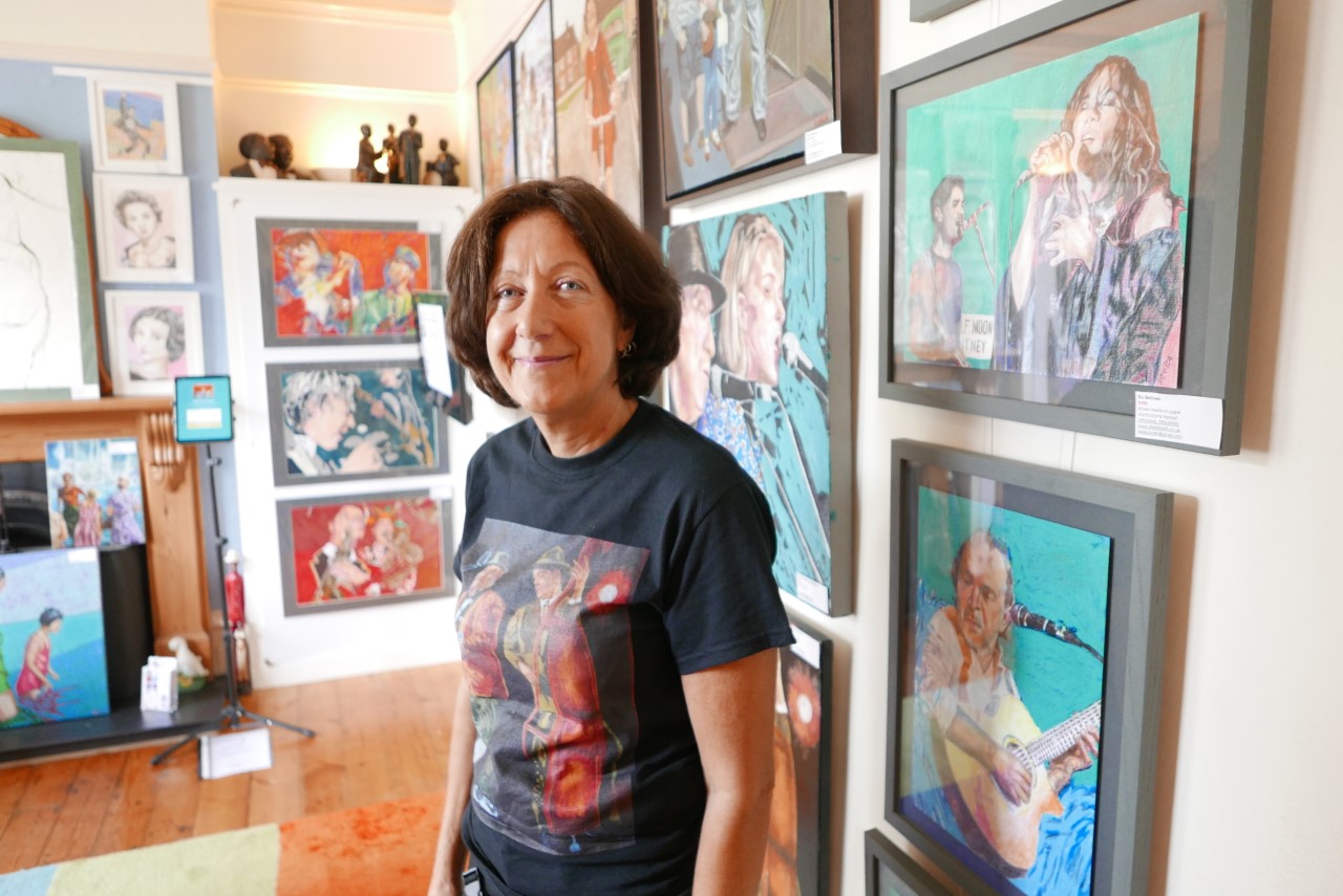 Stella Tooth standing in front of her 'performer art' paintings.